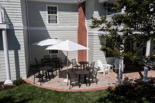 a patio with tables and chairs and umbrellas at The Princess Anne 200 Inn at Old Beach in Virginia Beach