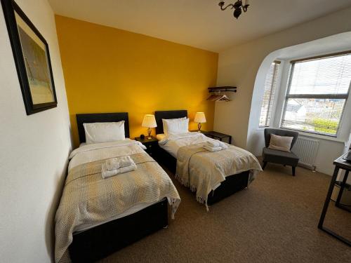 two beds in a room with yellow walls at Watermead House in Chard