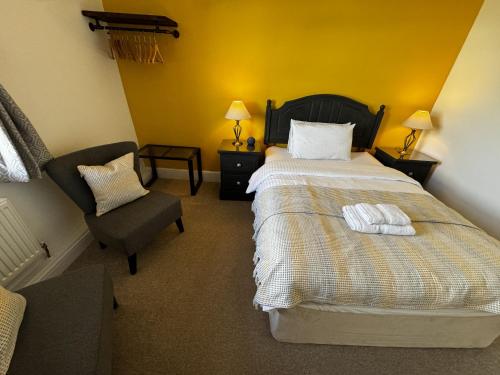 a hotel room with a bed and a chair at Watermead House in Chard