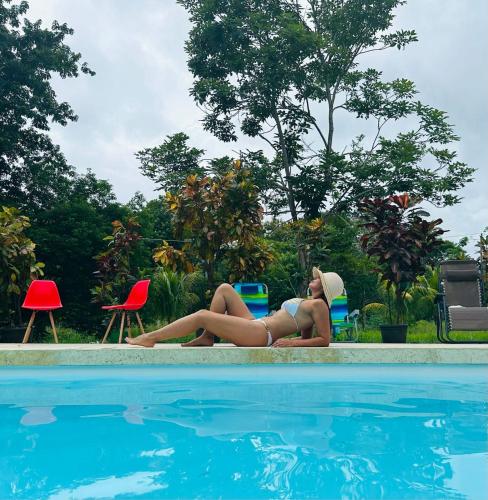 a woman in a bikini laying next to a swimming pool at Villas La Paillote Costa Rica in Puntarenas
