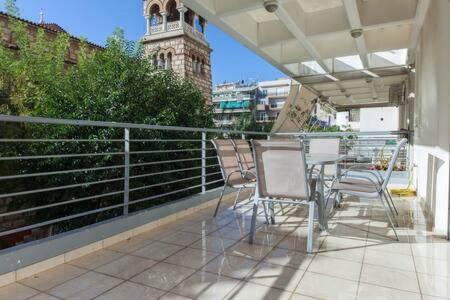 a balcony with chairs and a table and a clock tower at Scenic Balcony Apt in Vibrant Petralona in Athens