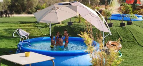 a group of three people standing in a pool with an umbrella at The Place in Albufeira