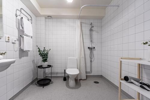 y baño blanco con aseo y ducha. en Stylish Studio Haven Ideal for Four Guests, en Estocolmo
