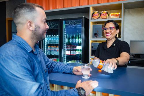 a man handing a woman a drink at a bar at ibis Styles Belém do Pará in Belém