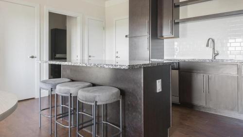 uma cozinha com três bancos de bar e um balcão em Landing Modern Apartment with Amazing Amenities (ID1180X314) em Creve Coeur