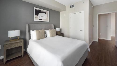 - une chambre avec un lit blanc et une table de nuit avec une lampe dans l'établissement Landing Modern Apartment with Amazing Amenities (ID8377X25), à Orlando