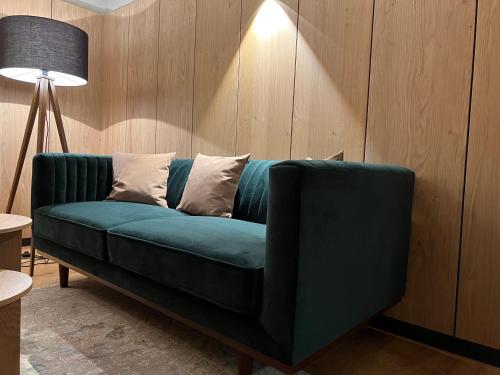 a green couch in a living room with a lamp at Aclavaldafur Apart in Nauders