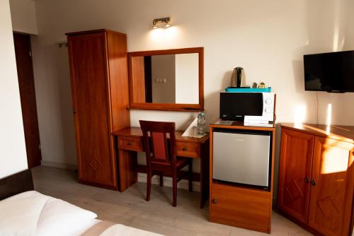 um quarto de hotel com uma secretária, uma televisão e uma cama em Villa Plazowa 6 em Rewa
