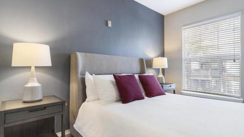 ein Schlafzimmer mit einem Bett mit lila Kissen und einem Fenster in der Unterkunft Landing Modern Apartment with Amazing Amenities (ID8377X83) in Grapevine