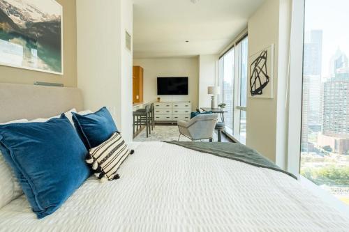 a bedroom with a bed with blue pillows and a television at Landing Modern Apartment with Amazing Amenities (ID634) in Chicago