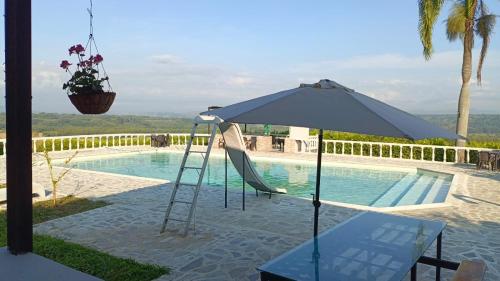 a chair and an umbrella next to a swimming pool at Finca Maratón Alto in Calarcá