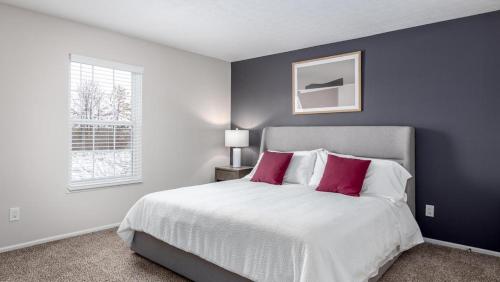 a bedroom with a large white bed with red pillows at Landing Modern Apartment with Amazing Amenities (ID9224X56) in Lewis Center