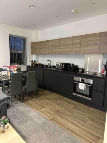 a kitchen with black cabinets and a table with chairs at Modern Elegance 2-Bedroom Apartment in Bolton