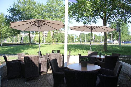 a patio with tables and chairs with umbrellas at Bastion Hotel Leiden Voorschoten in Leiden