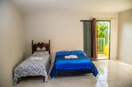 een slaapkamer met 2 bedden en een glazen schuifdeur bij POUSADA NEVOAR in Guaraciaba do Norte