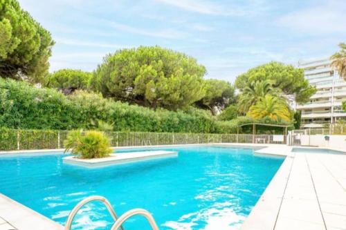 une piscine d'eau bleue et d'arbres dans l'établissement charmant appartement à deux pas de la mer, à La Grande Motte