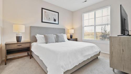 a white bedroom with a bed and a television at Landing Modern Apartment with Amazing Amenities (ID1981X99) in Greensboro