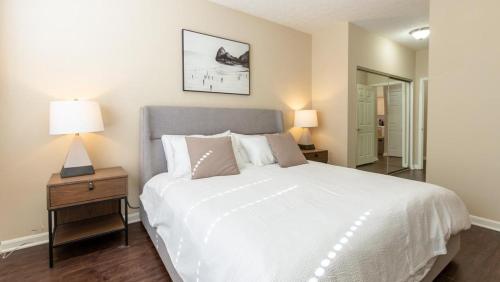 een slaapkamer met een groot wit bed en een nachtkastje met lampen bij Landing Modern Apartment with Amazing Amenities (ID8089X06) in Louisville