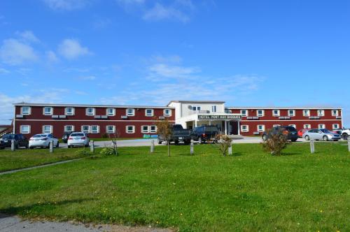 a large red building with cars parked in front of it at Hotel Port Aux Basques in Channel-Port aux Basques