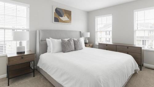 um quarto branco com uma cama e 2 janelas em Landing Modern Apartment with Amazing Amenities (ID1263X661) em New Albany