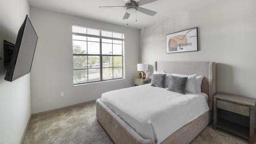 a white bedroom with a bed and a window at Landing Modern Apartment with Amazing Amenities (ID9660X22) in Orlando