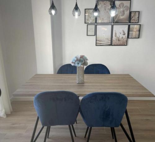 uma mesa de jantar com duas cadeiras azuis e um vaso com flores em Clauadris Home ideal para familias em Águilas