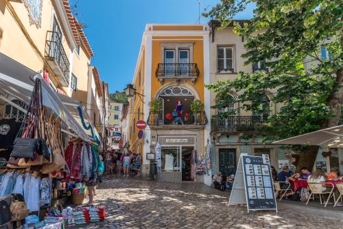 a street in a city with people sitting in cafes at Casa da Vila in Sintra