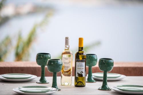 una mesa con 2 botellas de vino y copas verdes en La Casa Del Sol Villa en Aegenitissa