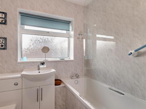 uma casa de banho com um lavatório, uma banheira e uma janela em 3 Bed in Heacham 84044 em Heacham