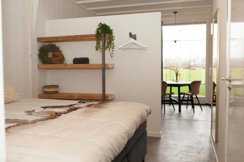 1 dormitorio con 1 cama y comedor con mesa en Het Groeneveld, en Oudkarspel
