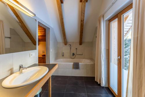 ein Badezimmer mit einem Waschbecken und einer Badewanne in der Unterkunft Hotel Restaurant Seehaus Mountain Lake Resort in San Giuseppe in Anterselva
