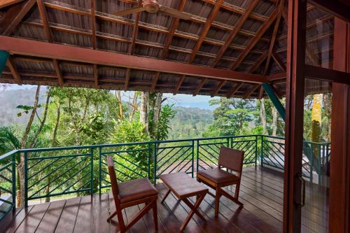 a balcony of a house with two chairs and a table at Forest Canopy Thekkady in Thekkady