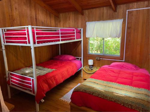 a bedroom with two bunk beds and a window at Parador Darwin in Cucao