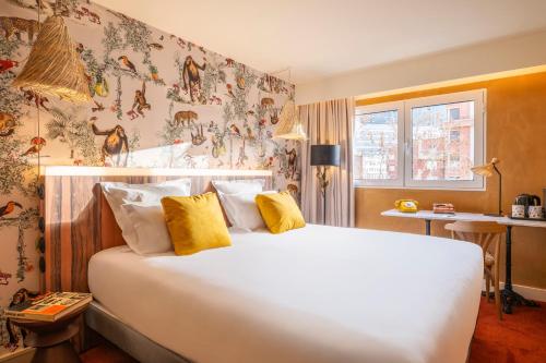 ein Schlafzimmer mit einem großen weißen Bett mit gelben Kissen in der Unterkunft Kopster Hotel Paris Porte de Versailles in Paris