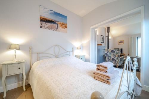 a bedroom with a white bed with towels on it at The Tap Room by Big Skies Cottages in Blakeney