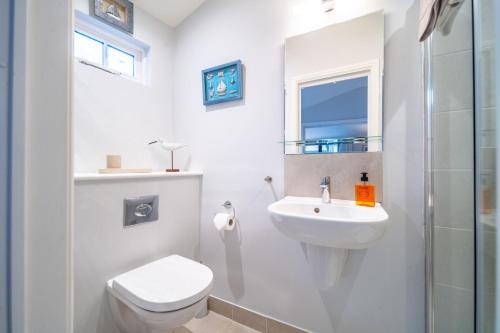 a white bathroom with a toilet and a sink at The Tap Room by Big Skies Cottages in Blakeney