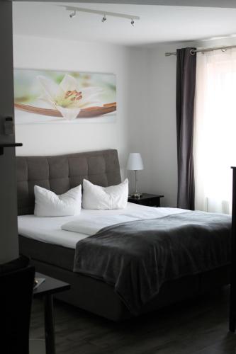 Hotel Restaurant Erbprinz Walldorf في فالدورف: غرفة نوم بسرير كبير ومخدات بيضاء