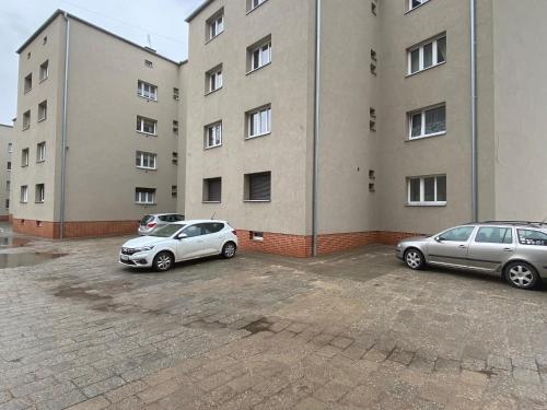 two cars parked in a parking lot in front of a building at ZB Apartment GREY Bytom Centrum Piekary Sląskie Siemianowice Chorzów in Bytom