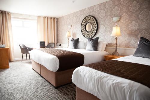 a hotel room with two beds and a mirror at Greville Arms Hotel Mullingar in Mullingar