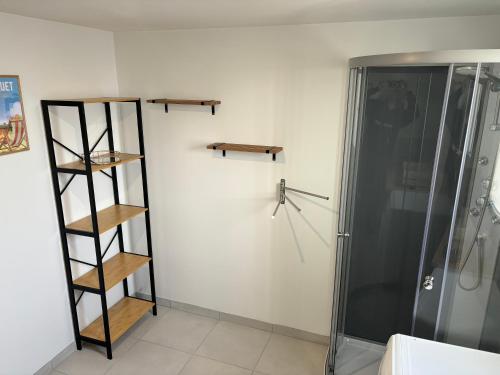 La salle de bains est pourvue d'une douche et d'étagères en bois sur le mur. dans l'établissement Grande maison 6-8 couchages, à Auchy-les-Mines