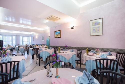 een eetkamer met tafels en stoelen met blauwe servetten bij Albergo Villa Denny in Rimini