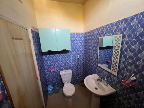 a blue tiled bathroom with a toilet and a sink at Chez Mimi in Toubab Dialaw