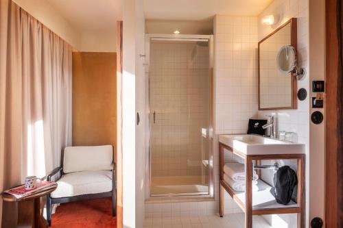 a bathroom with a shower and a sink and a chair at Kopster Hotel Paris Porte de Versailles in Paris