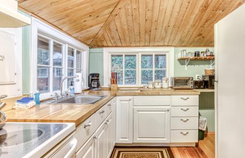 a kitchen with white cabinets and a wooden ceiling at The Cedars Cabin in Welches