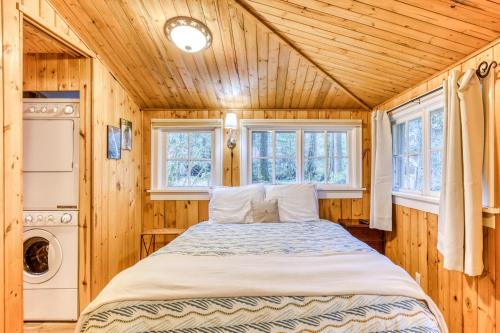 a bed in a room with wooden walls and windows at The Cedars Cabin in Welches