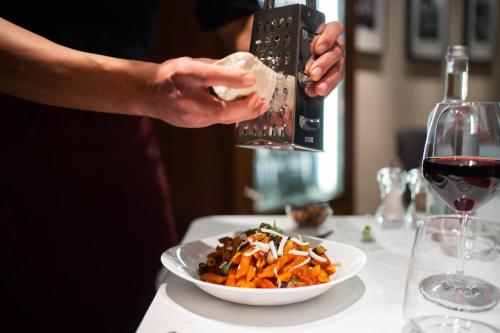 a person pouring a glass of wine over a plate of food at El Homs Palace Hotel in Comiso