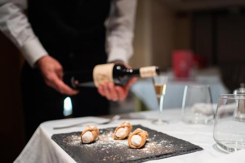 a man holding a bottle of wine on a table with food at El Homs Palace Hotel in Comiso