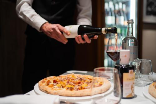 a person pouring a bottle of wine over a pizza at El Homs Palace Hotel in Comiso