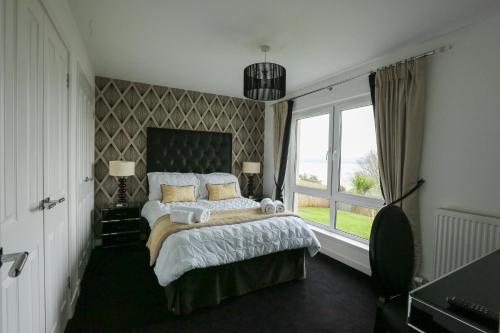 Un dormitorio con una cama grande y una ventana en Viewpoint Villa - Luxury 4 Bedroom villa with elevated views en Rothesay