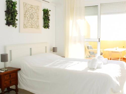 a white bedroom with a large white bed and a table at Magnífico ático frente al mar en Ricón de la Victoria in Rincón de la Victoria